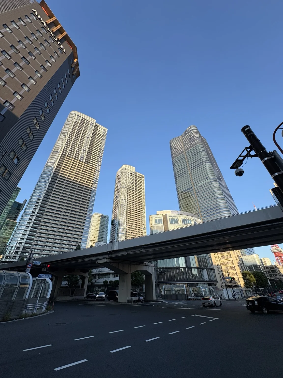 Azabudai Hills towers rising beyond an elevated road and a broad city intersection