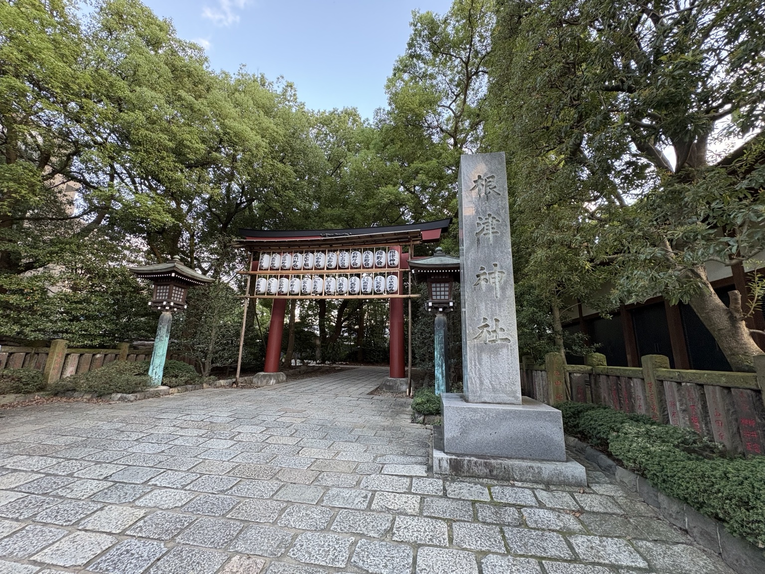Stone marker and entrance to Nezu Shrine beneath mature trees